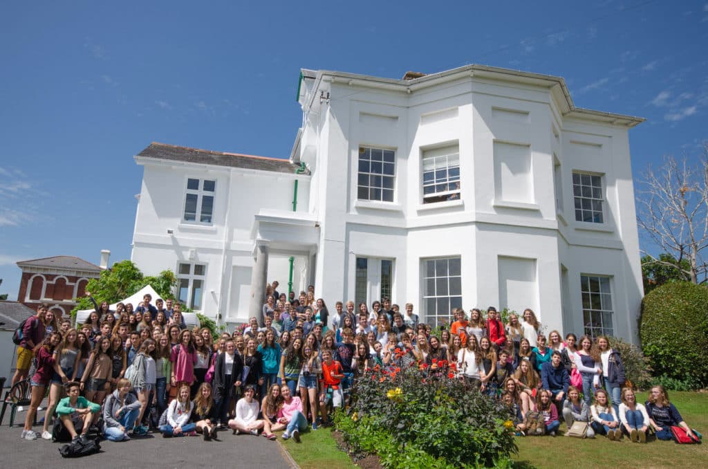 A group of international students standing and sitting in the front garden of the Isca School of English