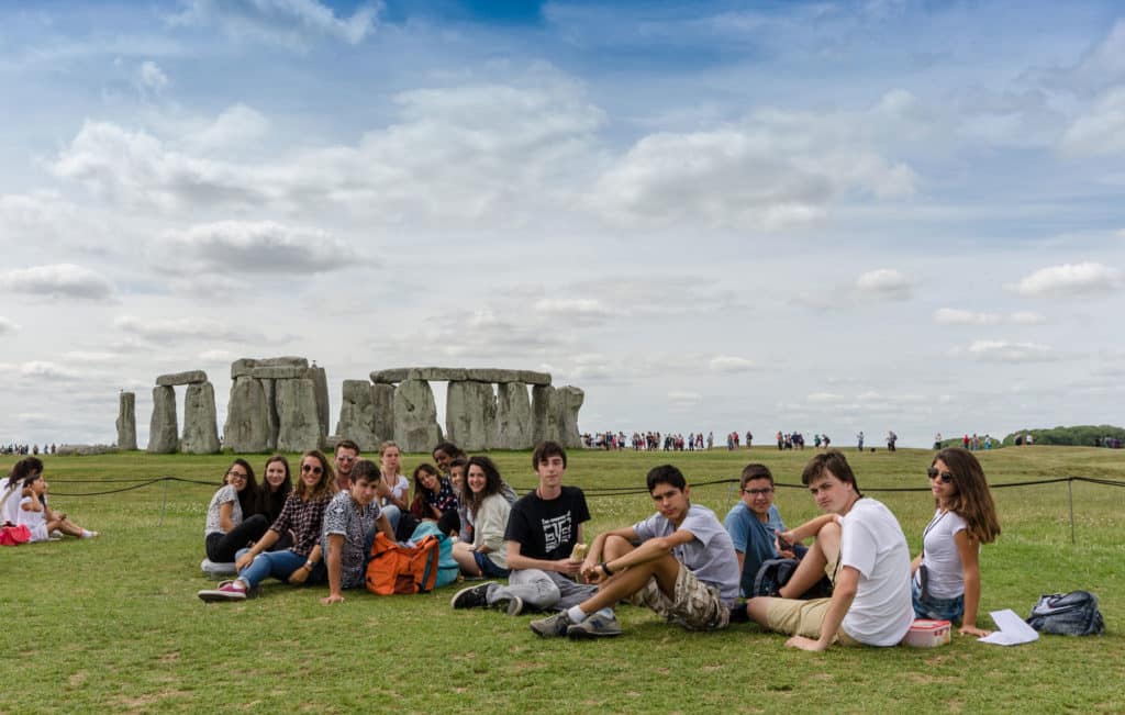 Group of Spanish and Italian students from the Isca School sitting down in front of Stonehenge