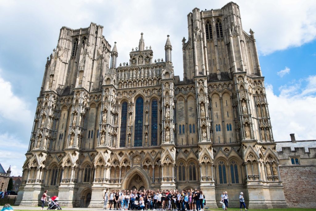 Uk excursions: Group of International students standing in front of Wells Cathedral with their teachers and group leaders