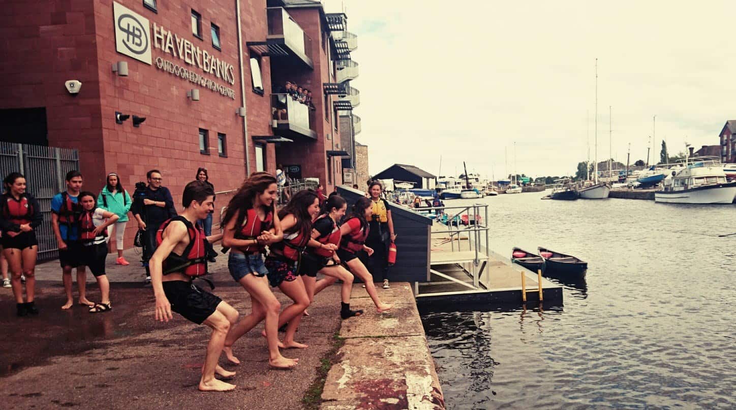 international students running in lifejackets to jump into the cold canal with instructor of Haven Banks watching on