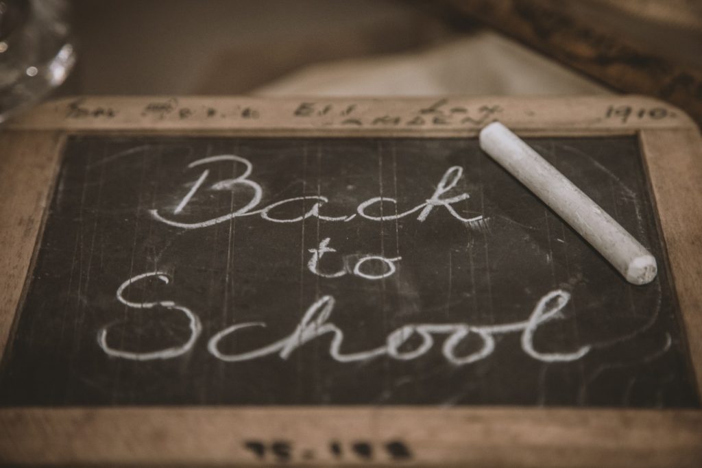 A hand held blackboard and a piece of white chalk. The sign says "back to school"